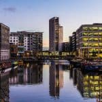Image of a canal with barges in the West Midlands with high rise buildings surrounding.