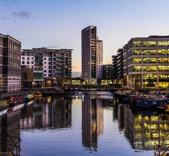 Image of a canal with barges in the West Midlands with high rise buildings surrounding.