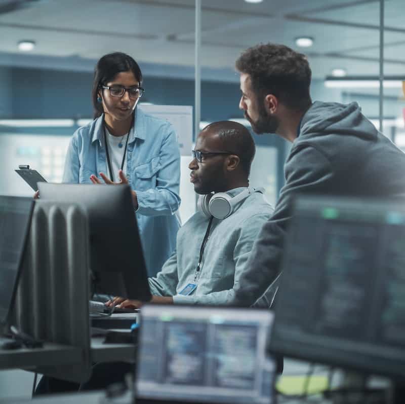 Diverse Group of Professionals Meeting in Modern Office: IT Programmers Use Computer, Talk Strategy, Discuss Planning. Specialists Create Innovative Software. Engineers Develop Inspirational App