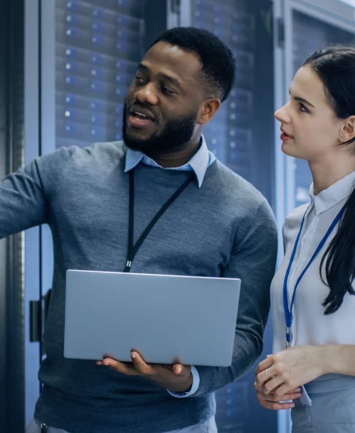Businessman holding a laptop showing woman colleague something.