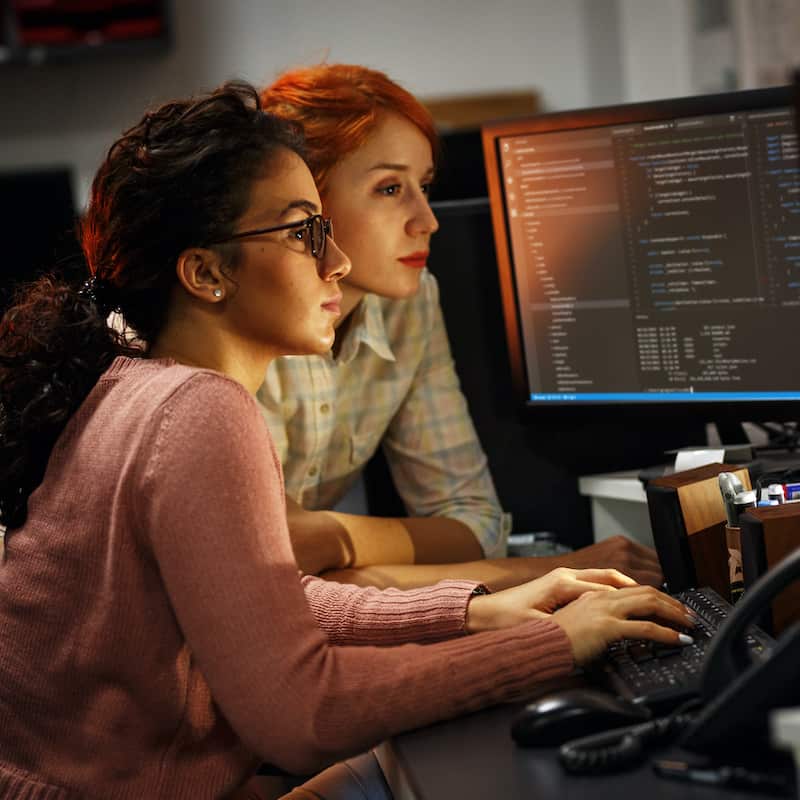 Two female website designers working on the coding for a website.