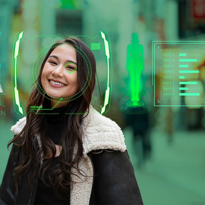 Woman smiling looking at a screen being scanned by artificial intelligence, which is producing data about her.